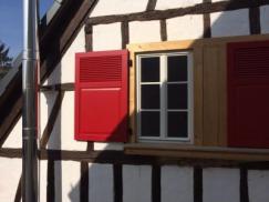 fenster-in-weiß-mit-roten-klapplaeden-bei-fachwerkhaus