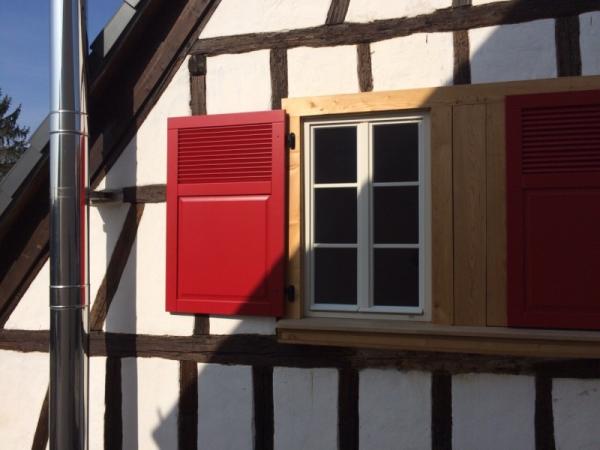 holzfenster-weiß-mit-klapplaeden-in-rot-bei-fachwerkhaus